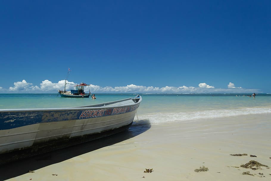 photo of white boat on seashore, trancoso, bahia, praia dos coqueiros