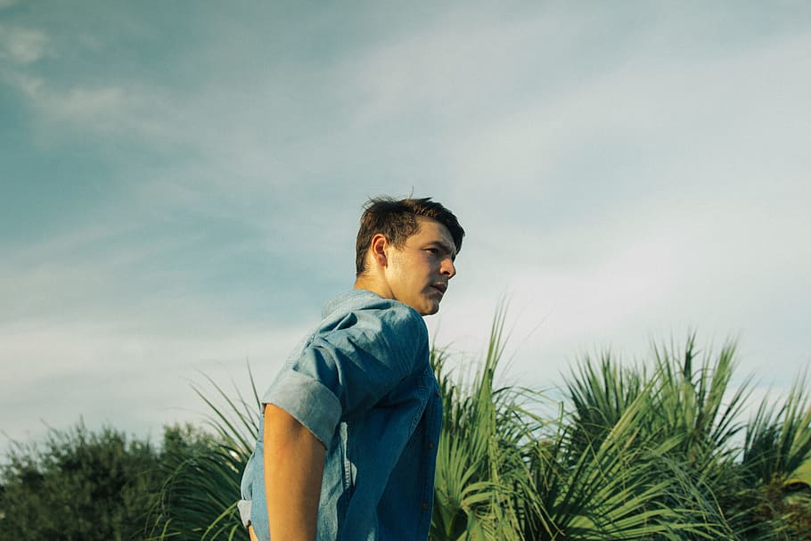 man wearing blue chambray top, man beside green leafed plant during daytime HD wallpaper