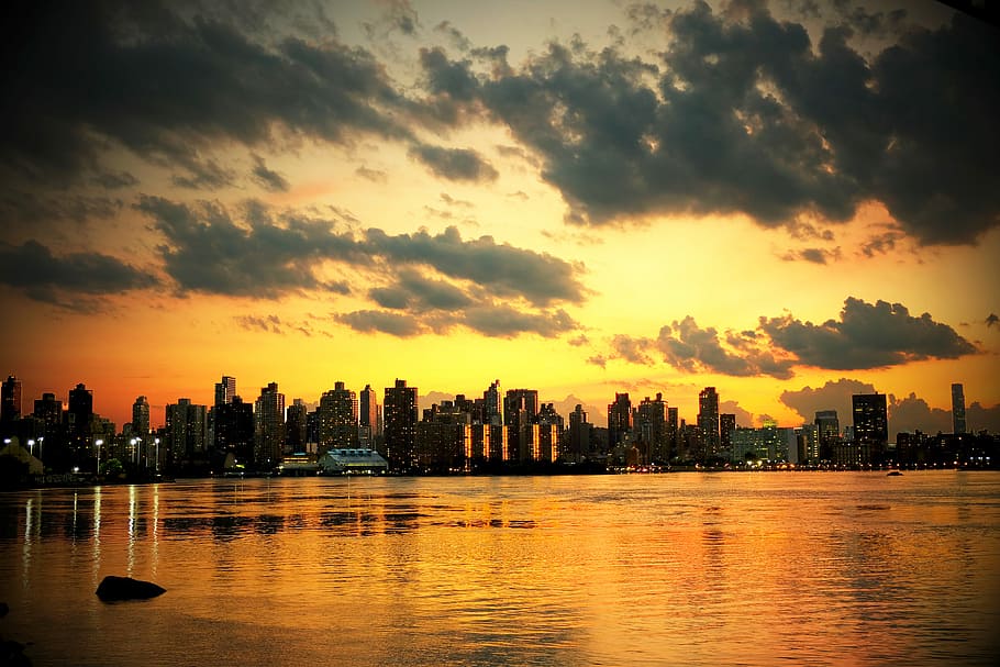 photo of cityscape under white clouds during golden hours, city buildings and body of water during sunset HD wallpaper