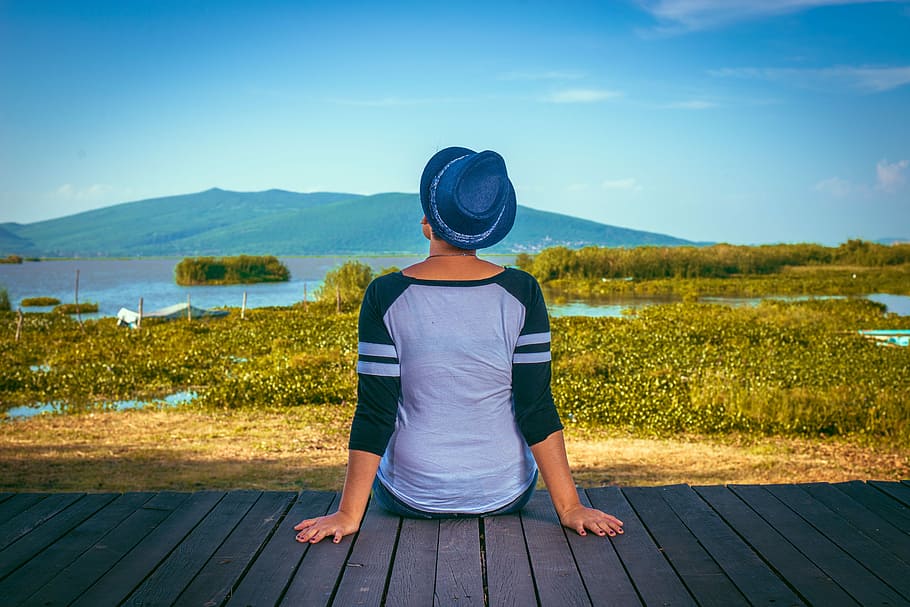 woman sitting on brown wooden dock taken at daytime, woman wearing raglan shirt and hat sitting on backyard balcony HD wallpaper