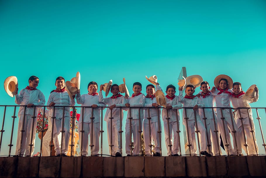 men standing on railings holding hats, group of children with matching shirts and sombreros HD wallpaper