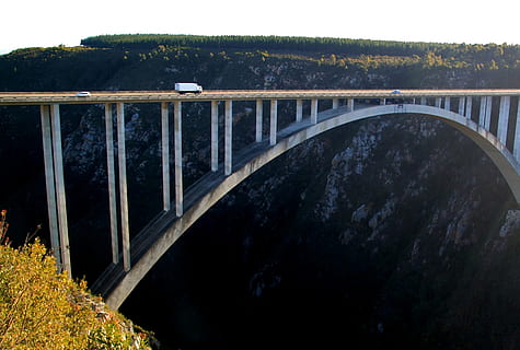 white truck passing on white concrete arch bridge at daytime HD wallpaper