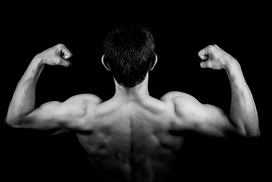 man flexes biceps on dark room, male, boy, a person, young, the muscles, HD wallpaper