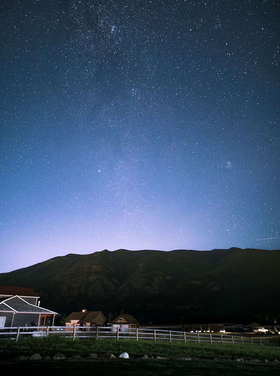 brown houses in front of hill under starry night, lighted house near fence HD wallpaper
