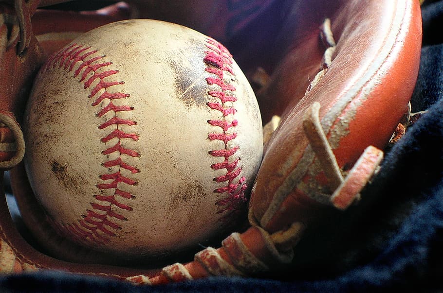 white and red baseball with brown leather baseball glove, softball