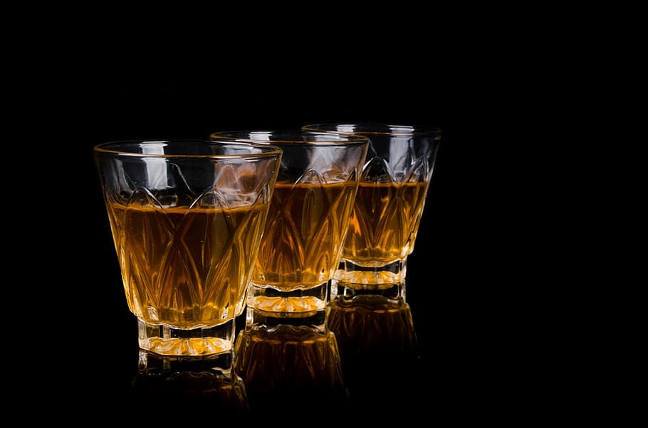 three clear crystal-cut rock glasses with brown liquid, bar, liquor