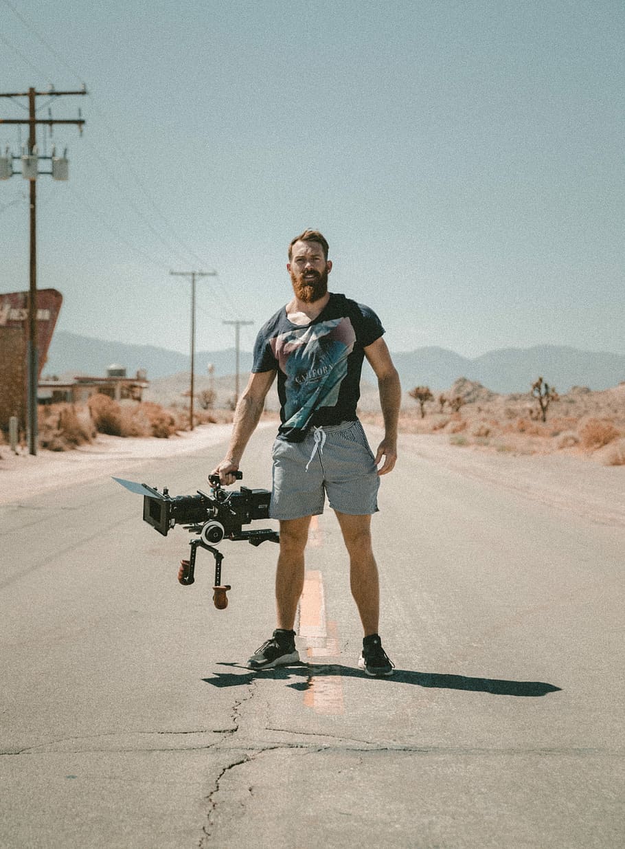 man holding camera standing on road during daytime, man carrying video camera standing on road, HD wallpaper