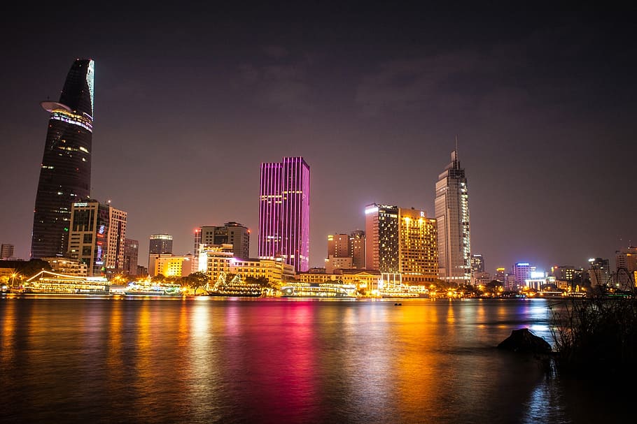 lighted high rise building beside body of water, saigon vietnam