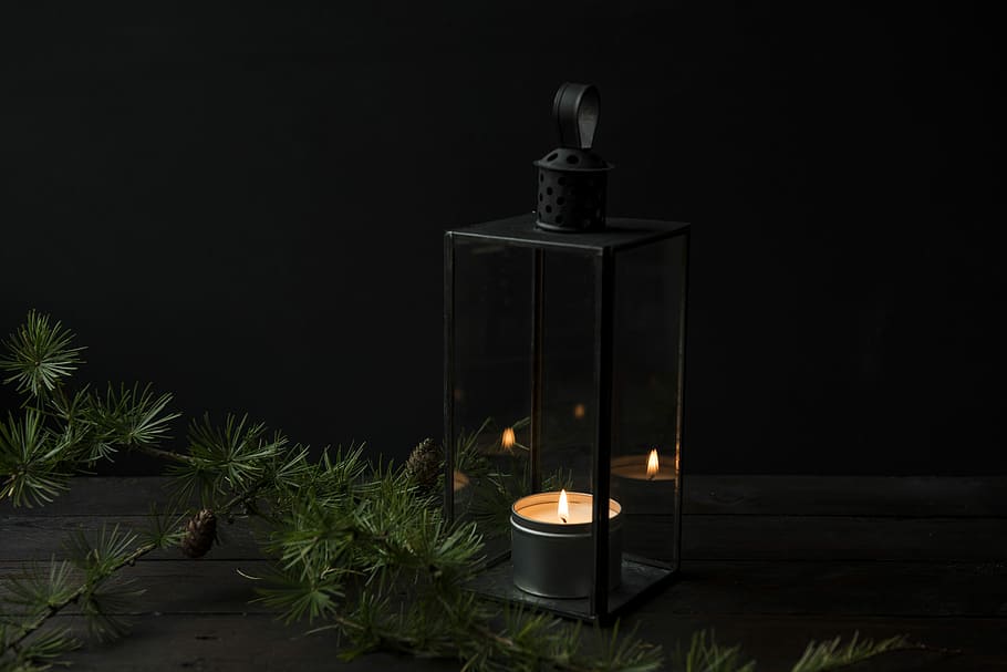 lighted candle inside black lantern holder, black metal framed tealight