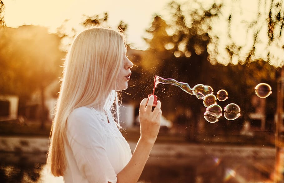 woman blowing bubbles during sunset, selective focus photography of woman blowing bubbles, HD wallpaper
