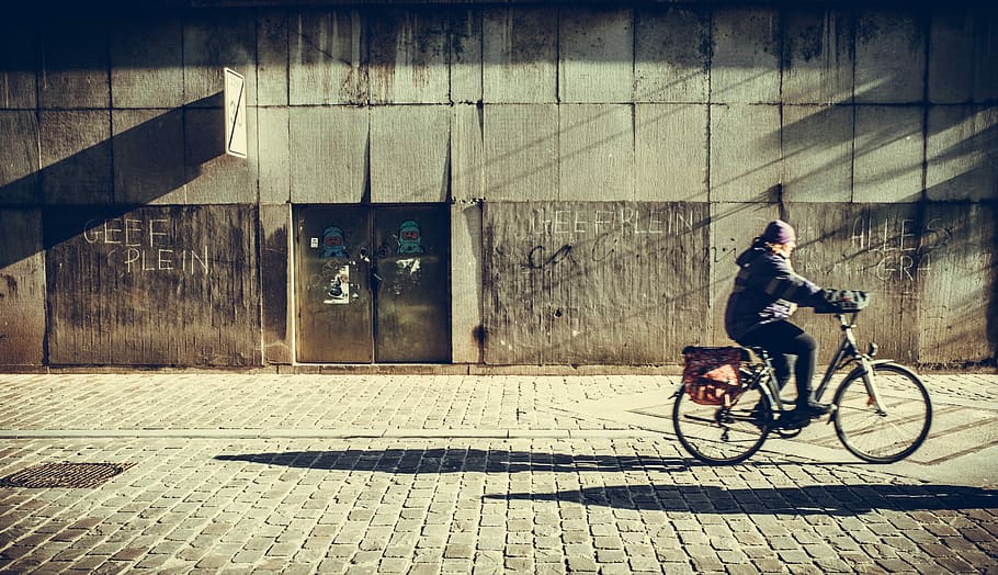 person riding bicycle near concrete wall, person riding on bicycle near building HD wallpaper