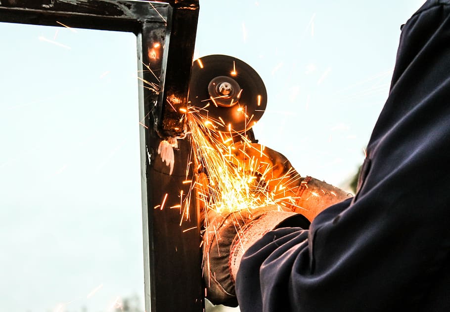person grinding metal during daytime, sparks, working, industry