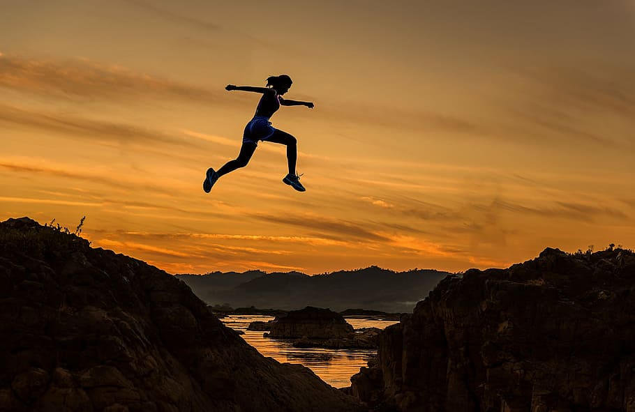 silhouette of woman jump on the rock, achieve, fluent, adventure