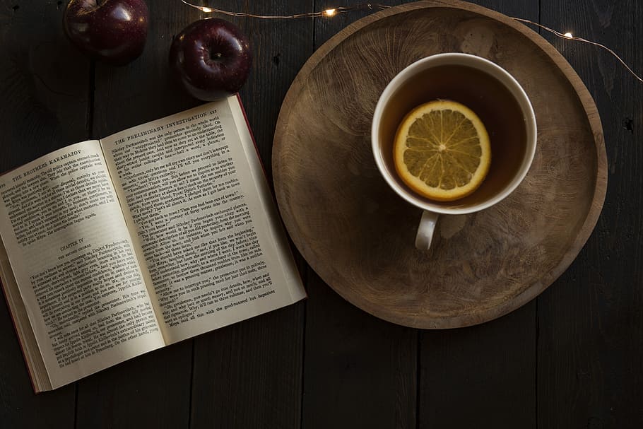 top view of open book and cup with lemon inside, white ceramic mug on top of round brown wooden tray beside book HD wallpaper