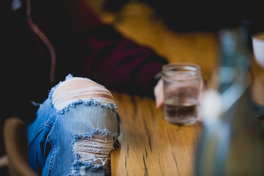 shallow focus photography of person holding drinking glass, tilt-shift lens photography of jeans HD wallpaper