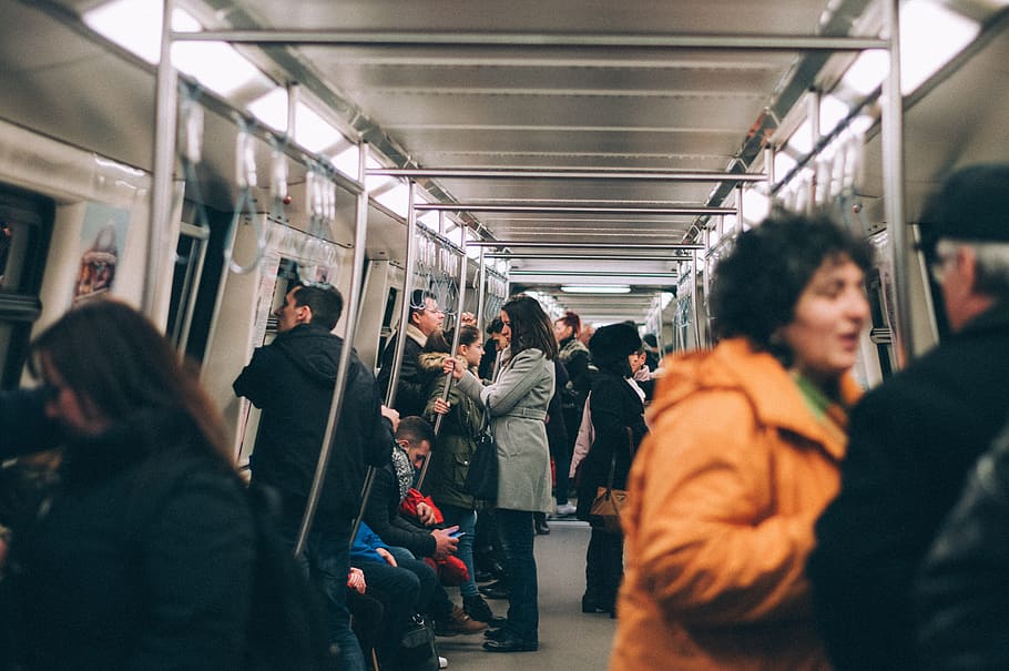 woman standing inside train surrounded by people, man and woman talking inside train