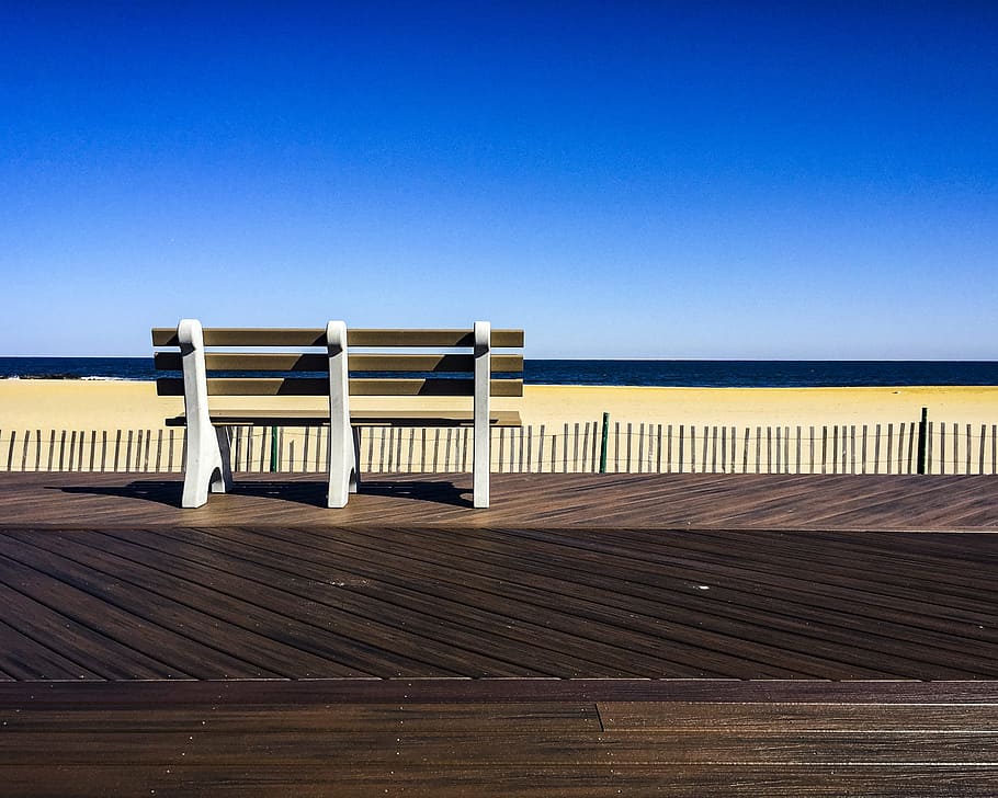 Brown-and-white Wooden Bench Facing Body of Water Under Clear Blue Sky HD wallpaper