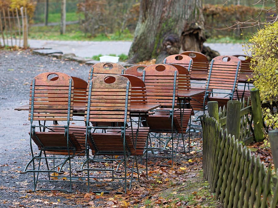 brown wooden and black metal chairs near gate, beer garden, dining tables