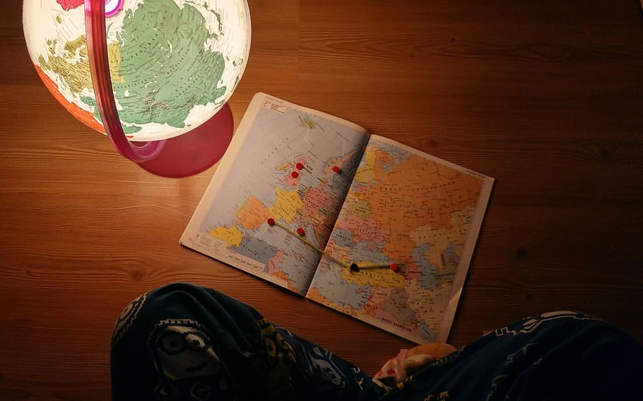 world map near desk globe on brown wooden panel, person sitting on floor with map beside glowing globe HD wallpaper