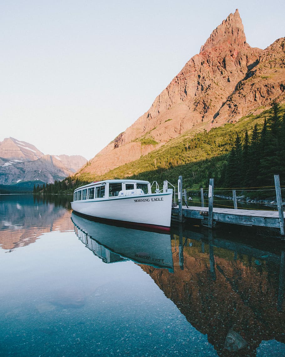 white and red boat on body of water near brown mountain, white motor boat on body of water near mountain during daytime HD wallpaper