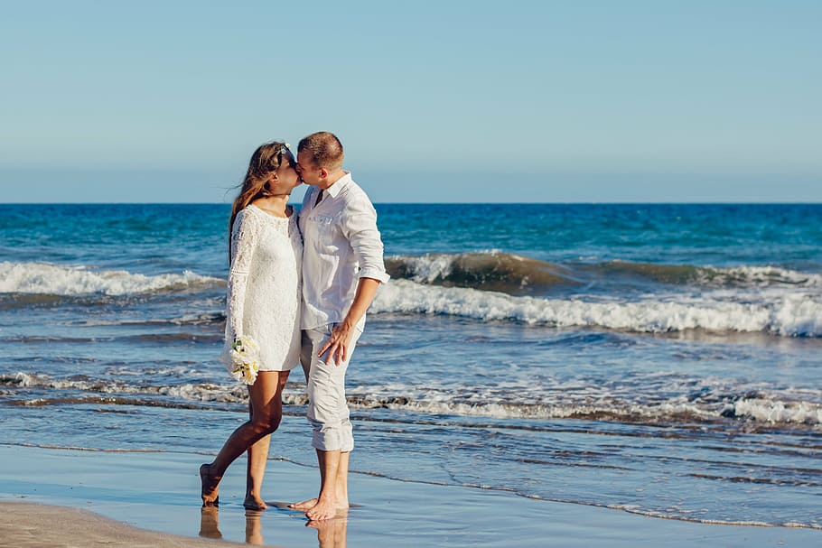 woman and man standing on shoreline kissing, love, a couple of