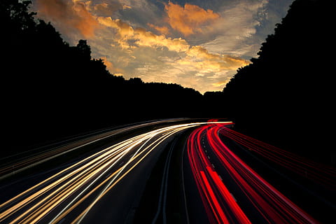low-exposure photo of light of vehicles on road under yellow cloudy sky HD wallpaper