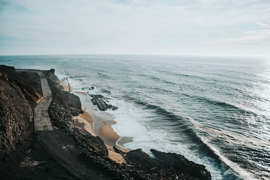 body of water near on the cliff, aerial view of coast with brown sandy beach during daytime HD wallpaper