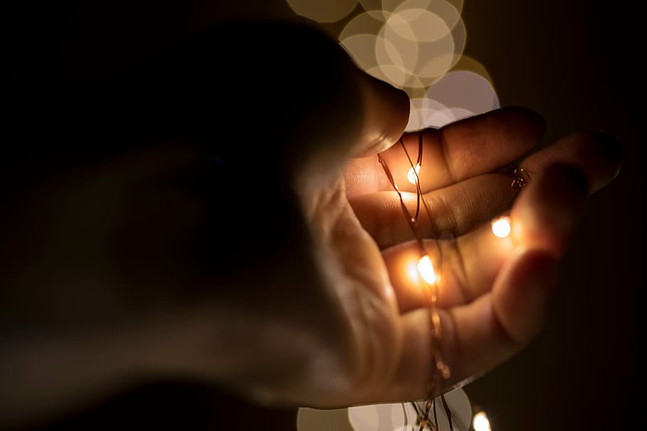 person holding string lights, black, dark, hand, christmas, holiday