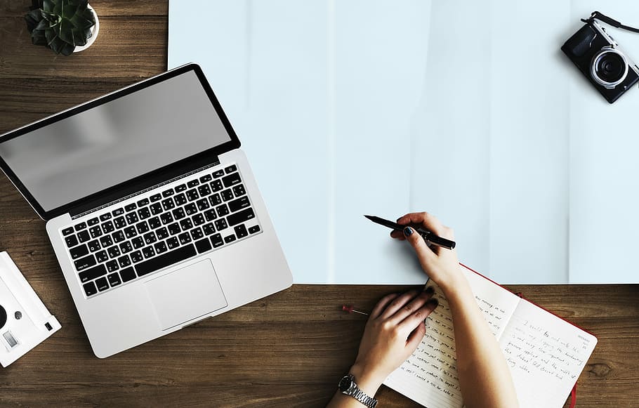 person about to write on chart beside MacBook Pro, laptop, camera HD wallpaper