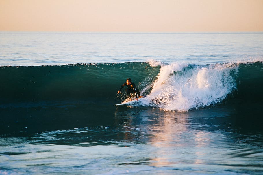 person performing surfing beside ocean waves during daytime HD wallpaper