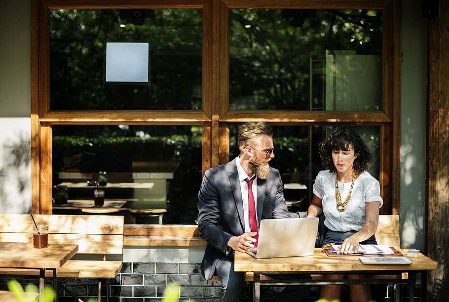Man and woman business meeting, man and woman sitting on bench in front of brown wooden table behind the window during daytime HD wallpaper
