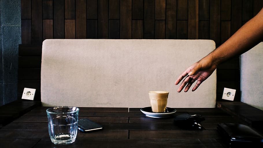 person tryng to grab a brown cup, person reaching paper cup on black wooden table HD wallpaper