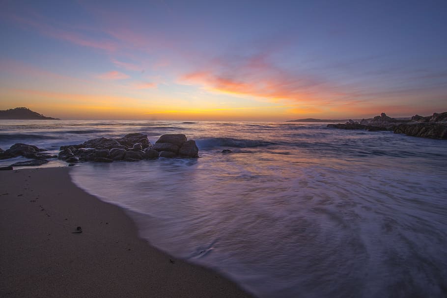 calm sea with rocks on seashore under orange sky, ocean, beach HD wallpaper