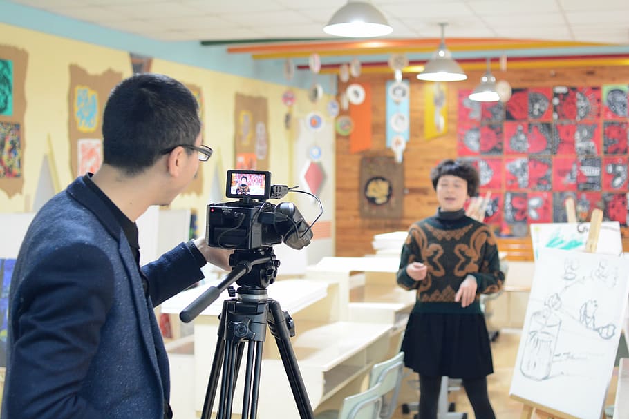 man taking video of woman standing inside of room, interview HD wallpaper