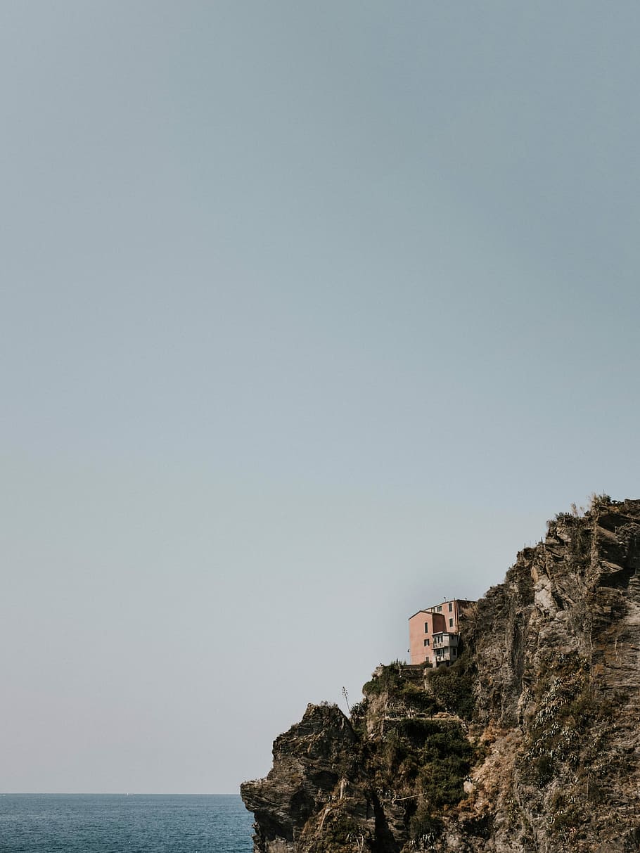 house on top of high ground near body of water, hill, cliff HD wallpaper