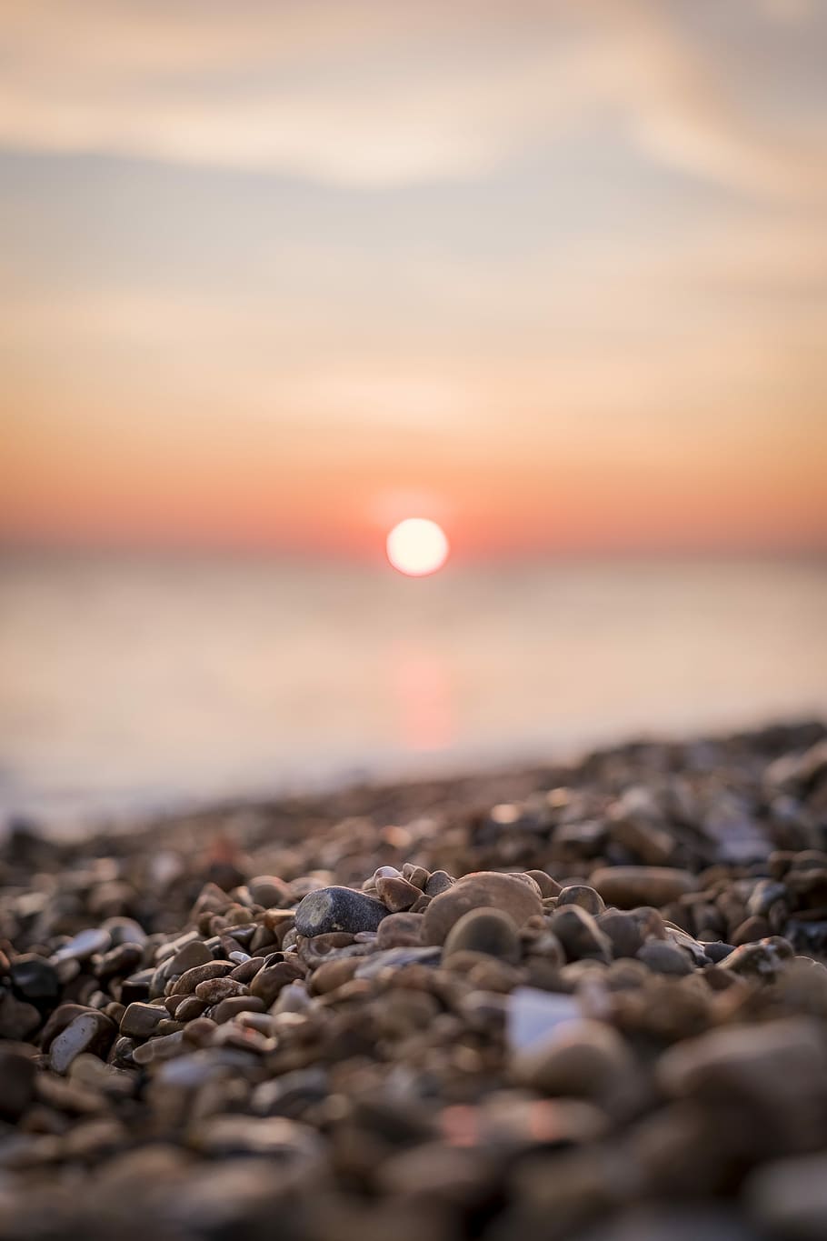 macro shot photography of brown pebbles, selective focus photography of pile of stone near seashore during sunset HD wallpaper