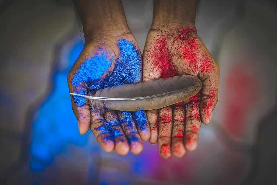 top view photography of brown feather on blue and red painted hands, person holding gray feather HD wallpaper