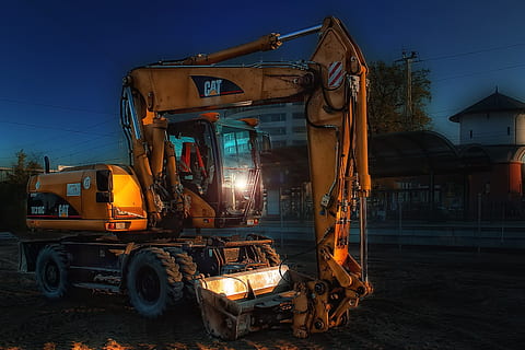 yellow Caterpillar excavator near concrete buildings, orange HD wallpaper