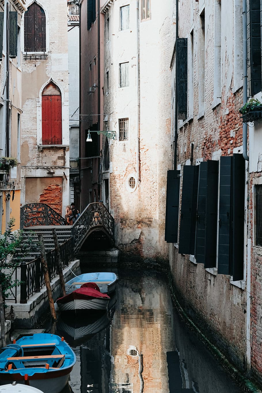 blue plastic boats in body of water beside concrete buildings, two blue boats beside brown concrete building HD wallpaper