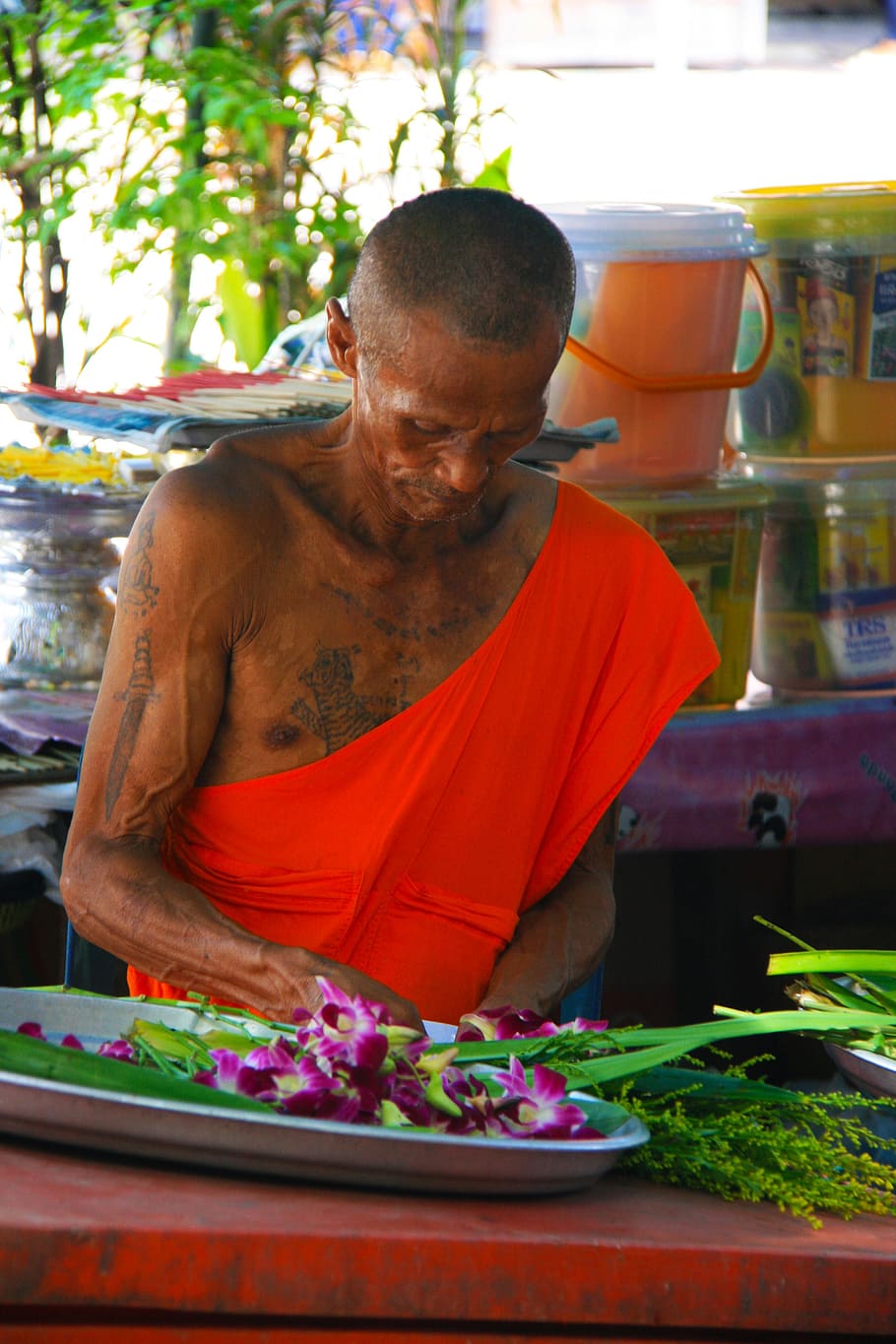 man in front purple orchids in oval gray tray, monk, orange HD wallpaper