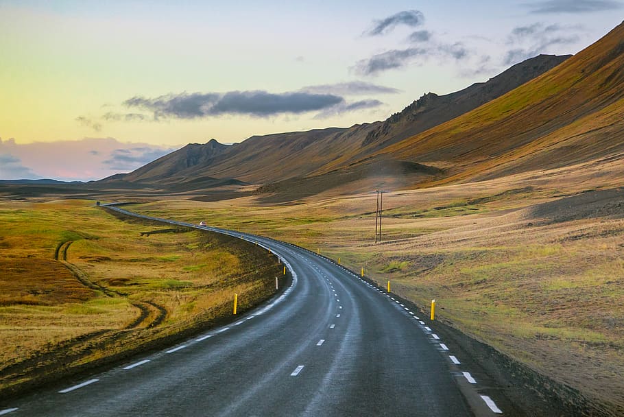 empty roadway between grass field during daytime, empty gray road near mountain HD wallpaper