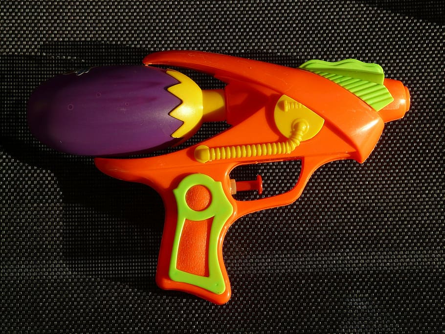 orange, green, and purple toy gun on black surface, water gun