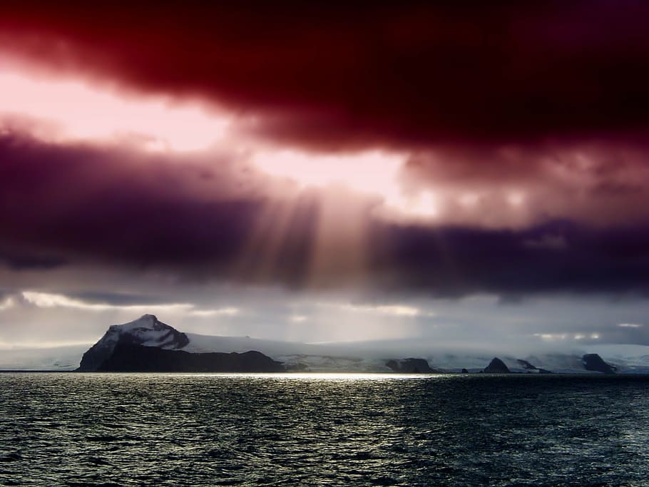 body of water near white and black island under green, gray, and purple sky HD wallpaper