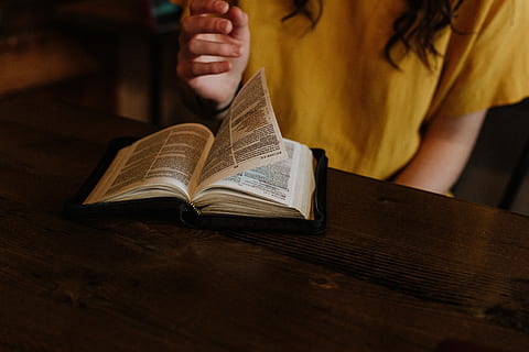 person reading Bible on top of brown wooden table, selective focus photography of woman flipping book page HD wallpaper