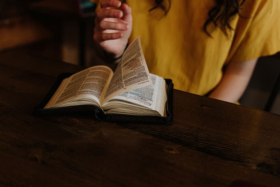 person reading Bible on top of brown wooden table, selective focus photography of woman flipping book page HD wallpaper