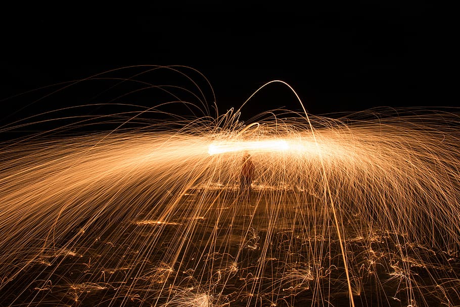 time-lapse photography of person using lit steel wool, low light photography of gold sparklers HD wallpaper