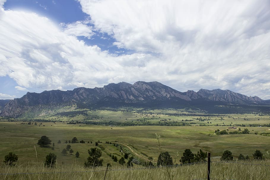 green grass field with mountains during daytime, mountain under the cloudy sky HD wallpaper