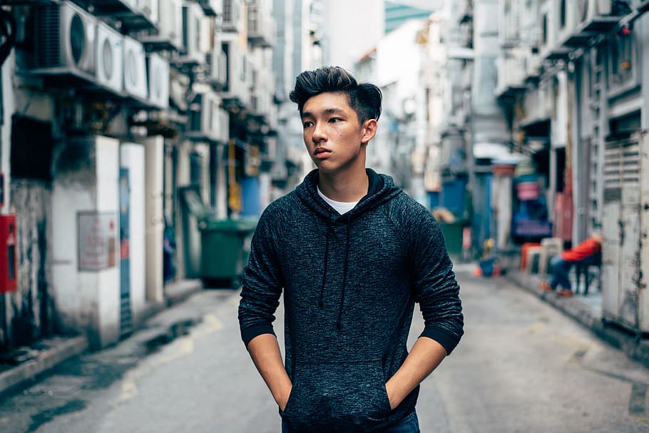Back Alley Way, selective focus photography of man wearing black pullover hoodie holding pocket near houses