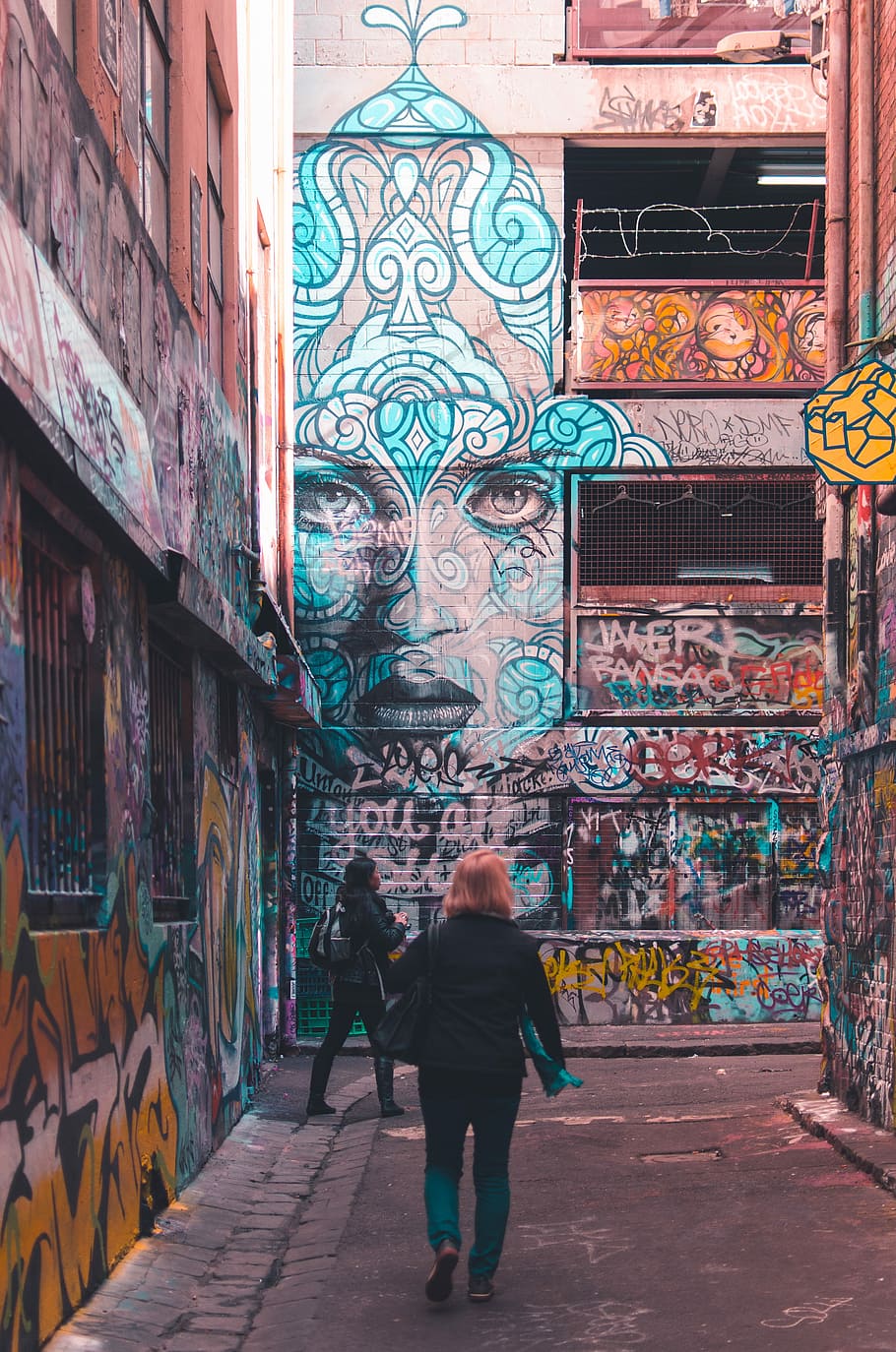 Detailed, two women walking buildings with graffitis during daytime HD wallpaper