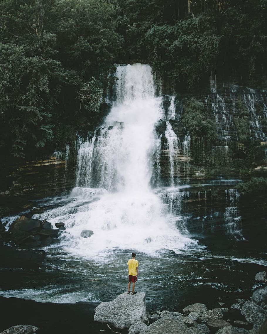 person standing on rock looking at water falls, man standing in front of cascading waterfalls HD wallpaper